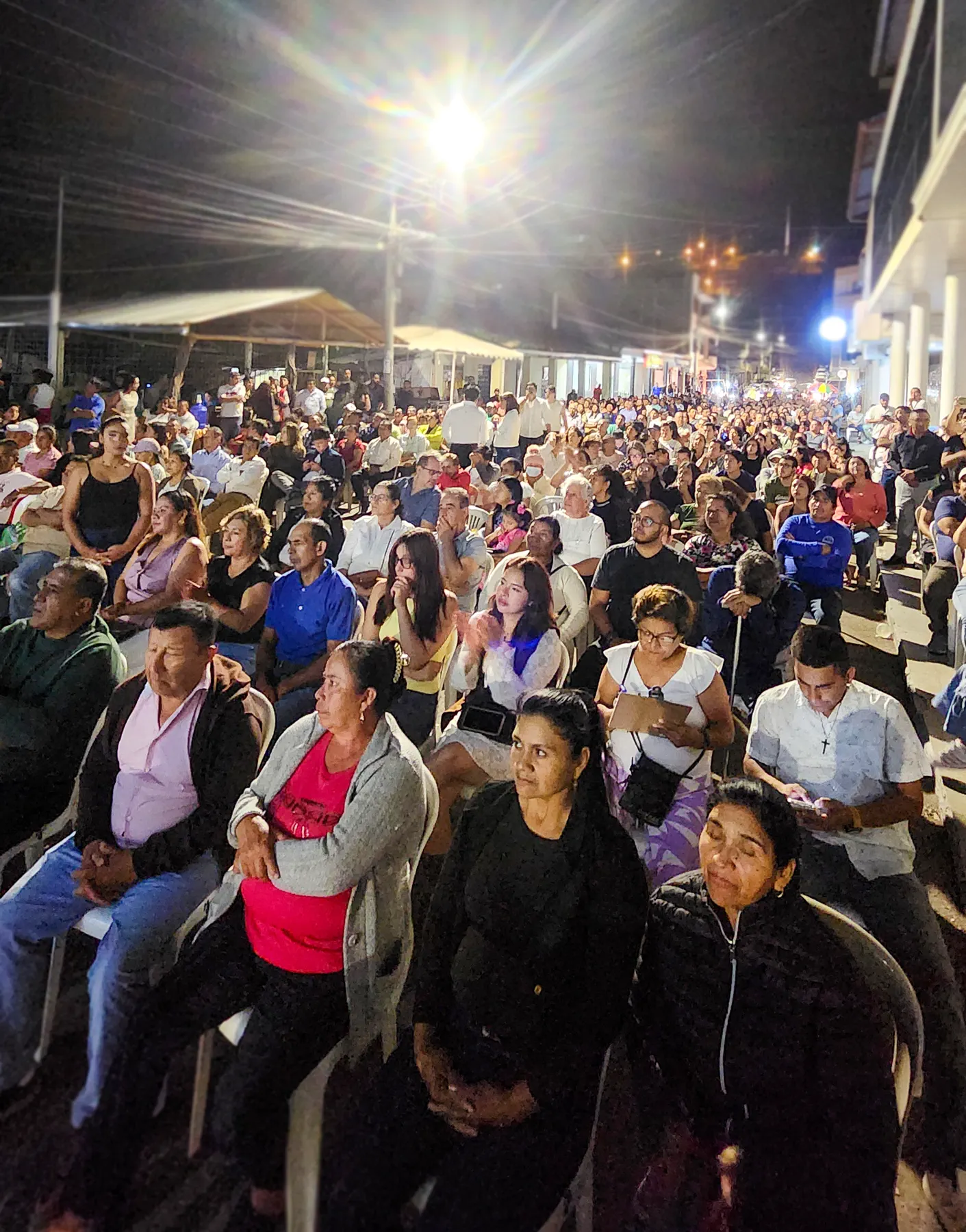 Vecinos sentados durante una reunión ciudadana realizada en la calle
