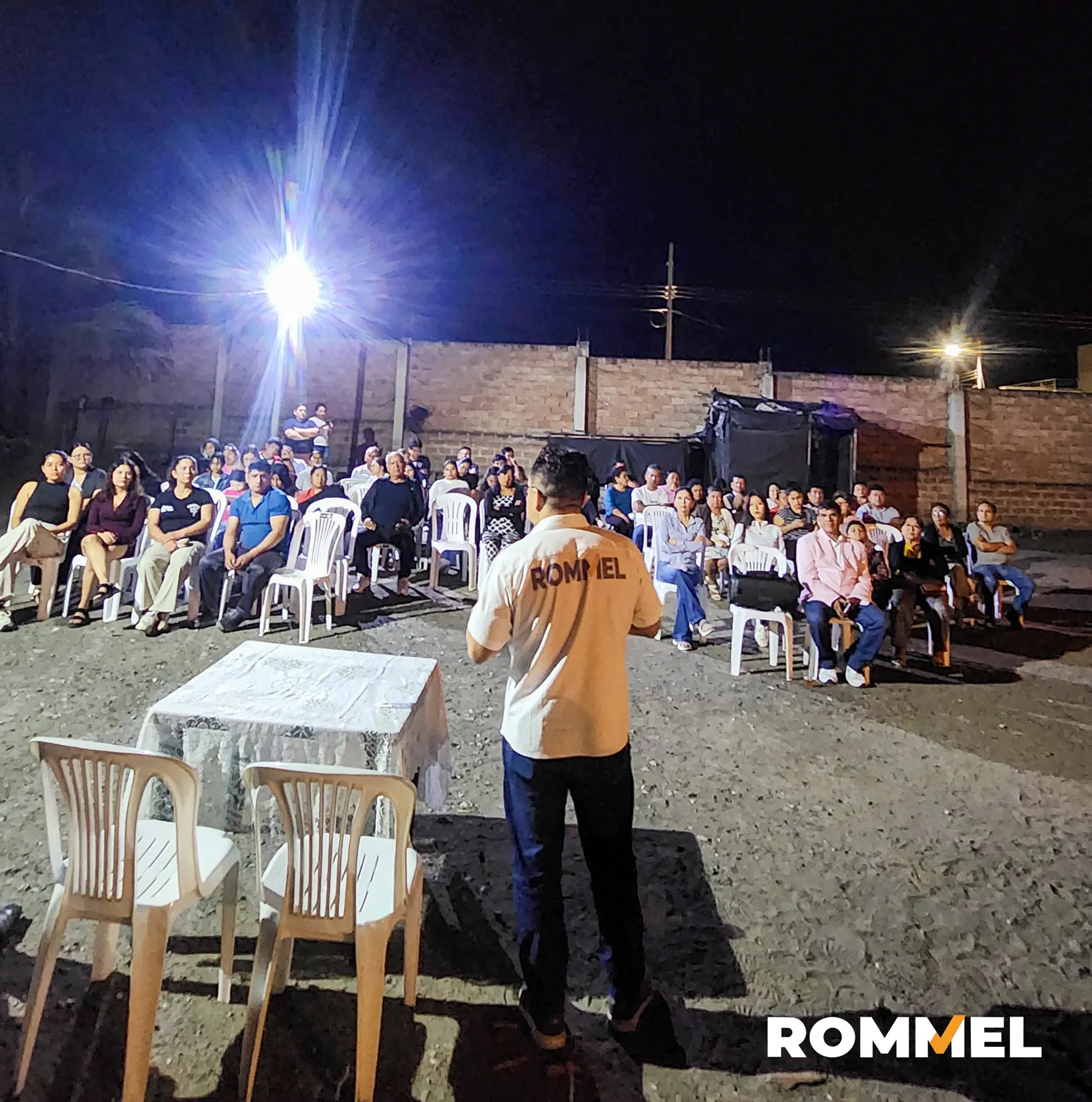 Rommel Durán conversando con vecinos reunidos alrededor de una mesa