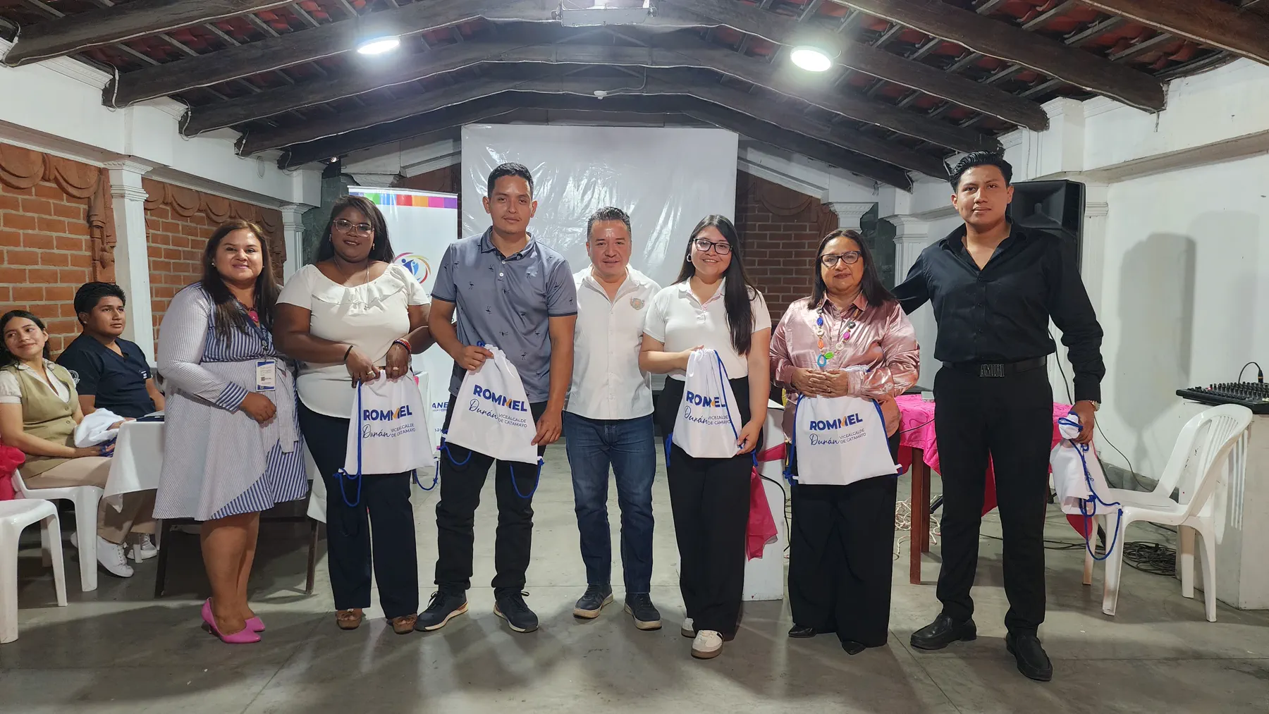 Vecinas y vecinos mostrando presentes recibidos en una reunión